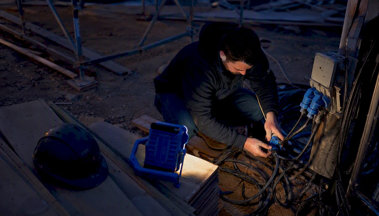 Business owner wiring power at construction site